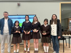 Group of students and teachers standing in a classroom with awards