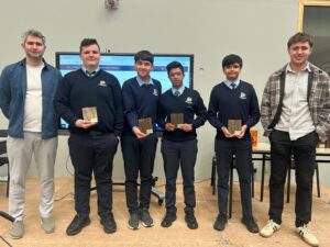 Group of students and teachers posing with awards on a stage.