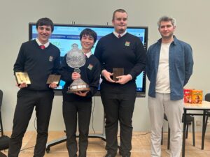 Math Competition winners with trophy and awards, smiling with their instructor.